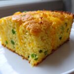 A close-up of a moist slice of Gluten-Free Cheddar Jalapeno Cornbread on a white plate.