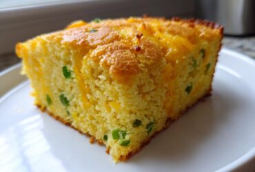 A close-up of a moist slice of Gluten-Free Cheddar Jalapeno Cornbread on a white plate.