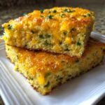 Two stacked squares of moist Gluten-Free Cheddar Jalapeno Cornbread topped with melted cheese and chives.