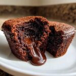 Close-up of a Gluten-Free Chocolate Lava Brownie Cup cut open, revealing rich, molten chocolate flowing out.