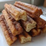 A close-up stack of crispy Gluten-Free Cinnamon Sugar Waffle Sticks coated heavily in cinnamon sugar.