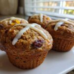 Four warm Gluten-Free Hot Cross Bun Muffins topped with a white icing cross, sitting on a white plate.
