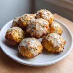 A pile of golden Gluten-Free Lemon Poppy Seed Donut Holes covered in a thick, speckled lemon glaze.