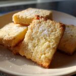 Close-up of four Gluten-Free Lemon Thyme Shortbread Cookies dusted with sugar on a light plate.