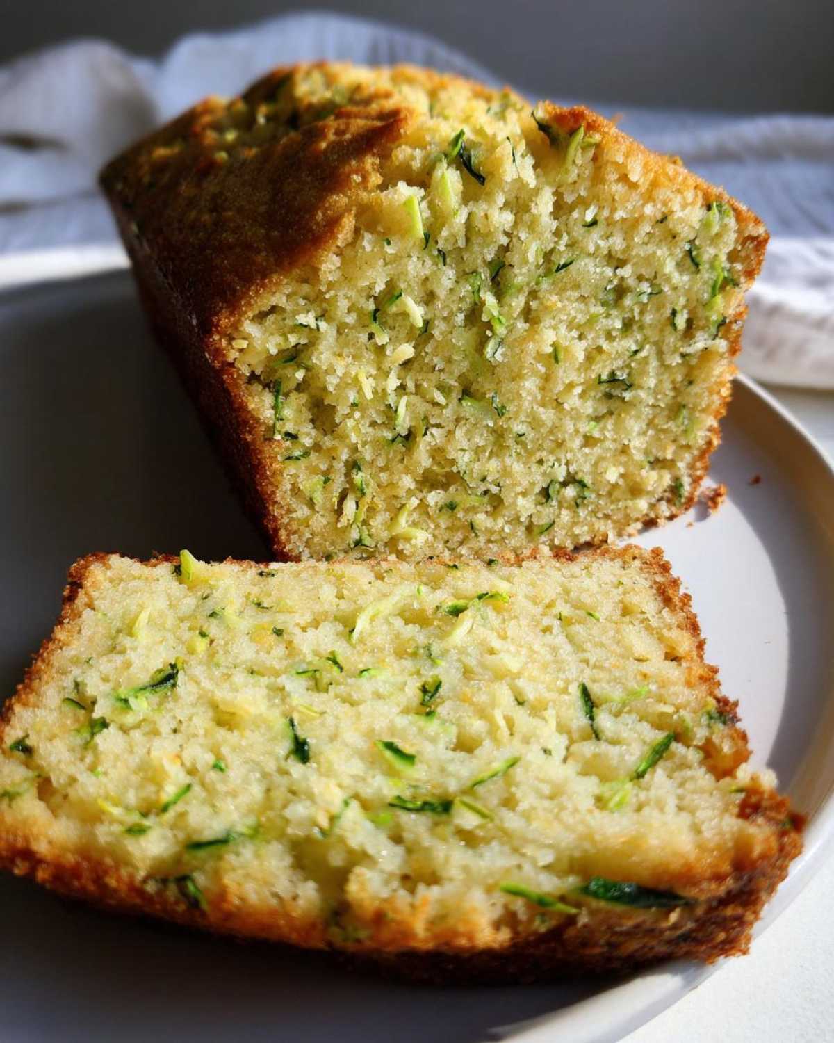 Close-up of a thick slice of moist Gluten-Free Lemon Zucchini Bread showing shredded green zucchini throughout the crumb.