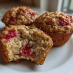 Close-up of three Gluten-Free Strawberry Oat Muffins, one broken open showing the moist interior and bright red strawberries.