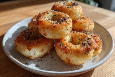 A stack of golden-brown High-Protein Cottage Cheese Bagel Bites topped with everything bagel seasoning on a speckled plate.