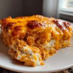A close-up of a square serving of Keto Creamy Buffalo Chicken Casserole with melted, bubbly orange cheese topping.