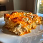 A close-up of a serving of Keto Creamy Buffalo Chicken Casserole, showing shredded chicken topped with melted orange cheese and blue cheese crumbles.