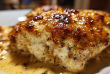 Close-up of a piece of Keto Creamy Garlic Parmesan Chicken Bake with a golden-brown, cheesy top and rich sauce.