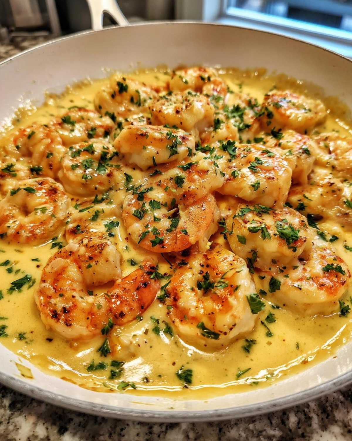 Close-up of perfectly cooked shrimp in a rich, yellow Keto Creamy Garlic Shrimp Skillet sauce, garnished with fresh parsley.