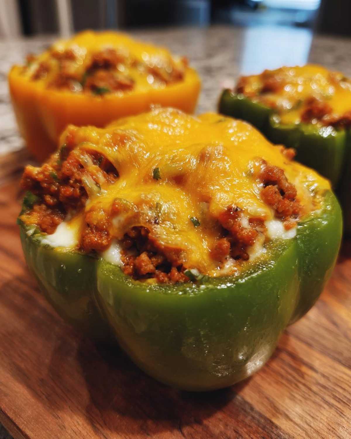 Close-up of a vibrant green bell pepper half filled with Italian sausage and topped with melted cheddar cheese for Keto Creamy Italian Sausage Stuffed Peppers.