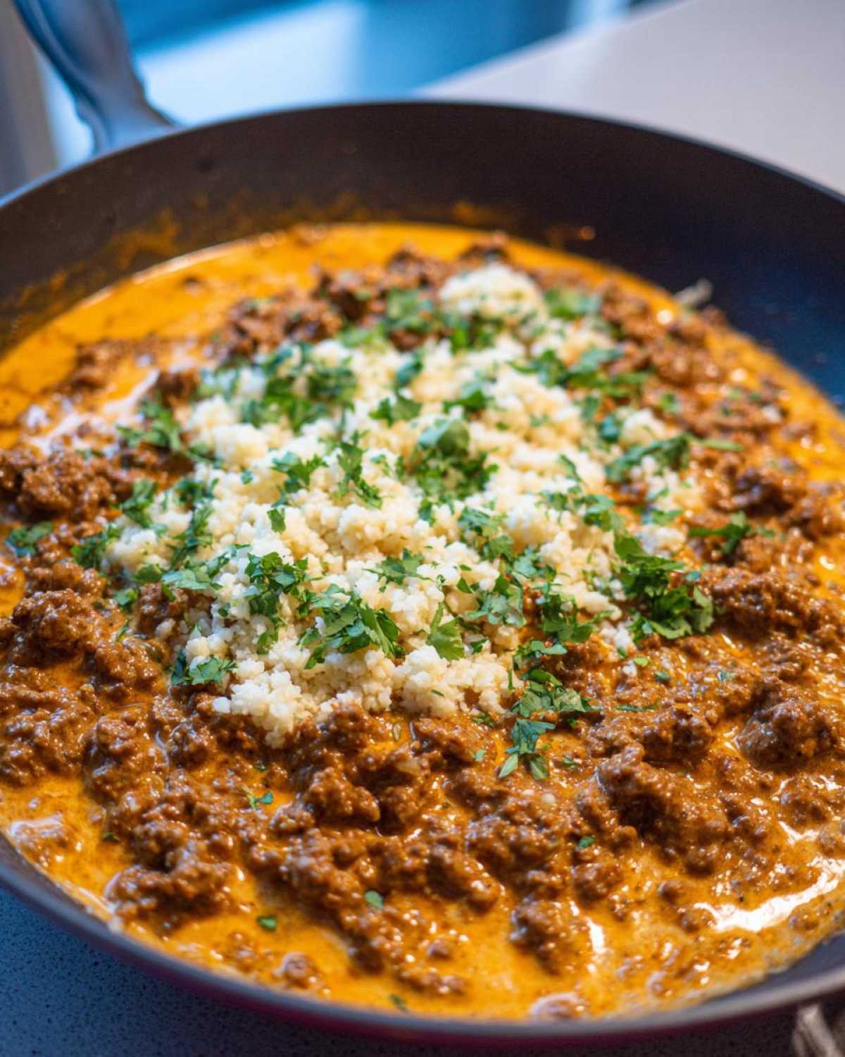Close-up of Keto Creamy Taco Skillet with seasoned ground meat in a creamy sauce, topped with cauliflower rice and fresh cilantro.