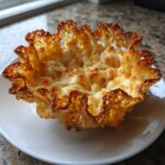 A single, crispy, golden-brown Keto Crispy Cheese Taco Shell Bowl resting on a small white plate.
