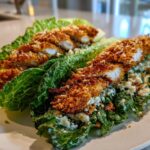 Two Keto Crispy Chicken Caesar Salad Wraps made with romaine lettuce leaves, topped with crispy chicken strips and Caesar dressing.