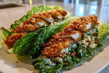 Two Keto Crispy Chicken Caesar Salad Wraps made with romaine lettuce leaves, topped with crispy chicken strips and Caesar dressing.