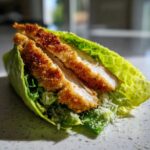 Close-up of a Keto Crispy Chicken Caesar Salad Wrap, showing crispy chicken strips inside a lettuce leaf with Parmesan cheese.