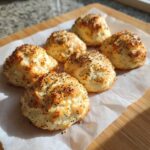 Six golden-brown Keto Everything Bagel Cloud Bread rolls topped with poppy seeds, resting on parchment paper.