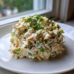 A scoop of creamy Keto Lemon Herb Chicken Salad garnished with fresh dill, served on a white plate.