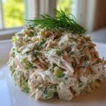 A mound of creamy Keto Lemon Herb Chicken Salad mixed with celery and fresh dill, topped with a sprig of dill.
