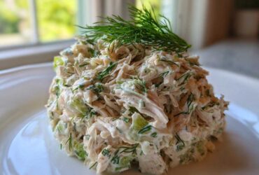 A mound of creamy Keto Lemon Herb Chicken Salad mixed with celery and fresh dill, topped with a sprig of dill.