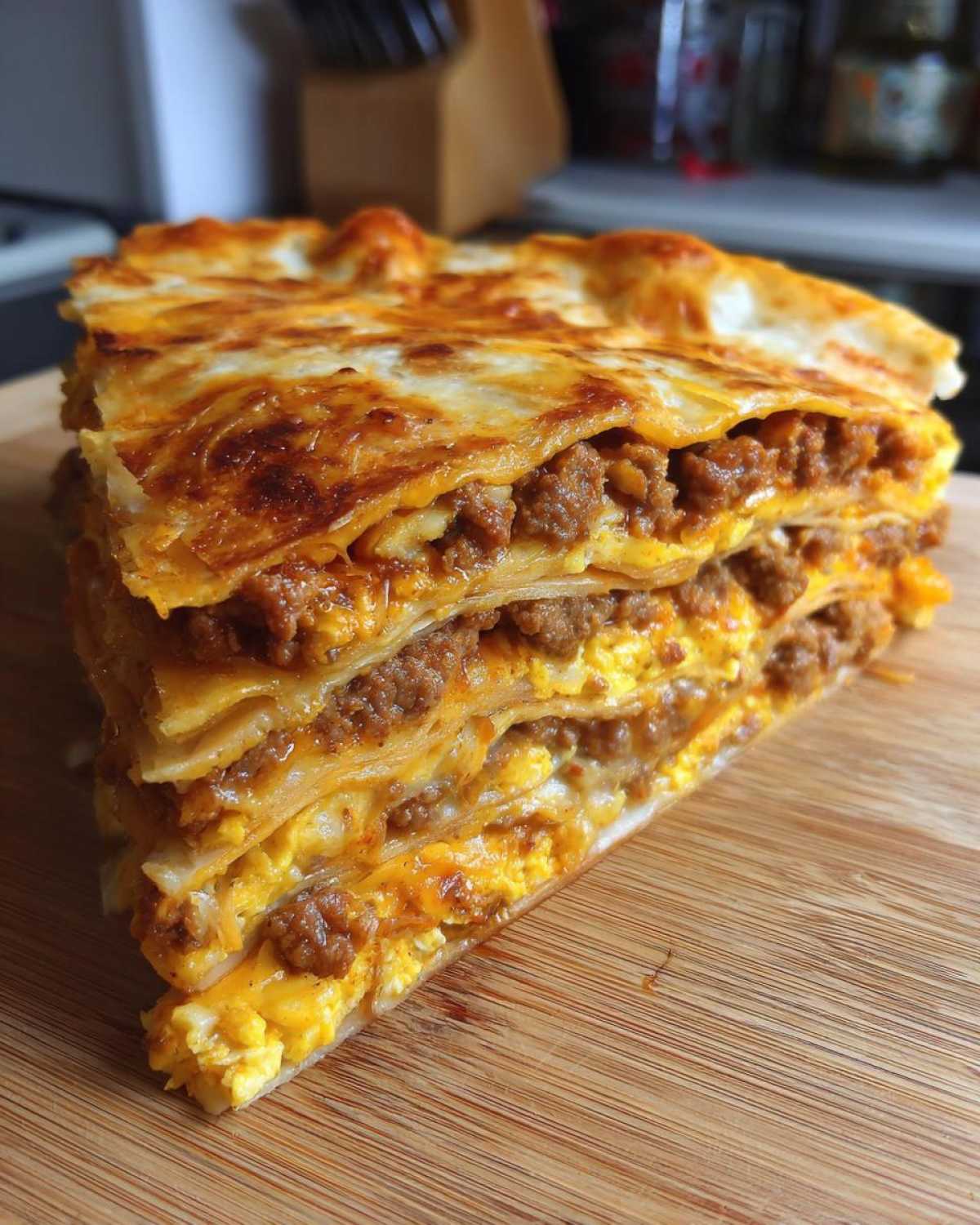 A thick, layered slice of Sheet Pan Breakfast Quesadillas showing melted cheese, scrambled eggs, and ground meat filling.