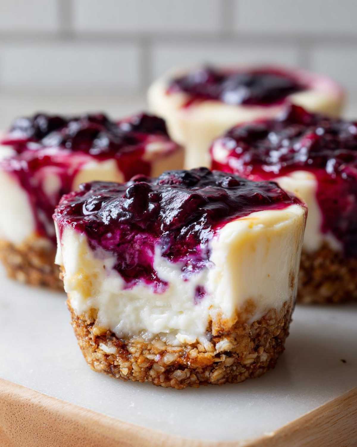 A close-up of a No-Bake Blueberry Cheesecake Oat Cup with a bite taken out, showing the creamy filling and oat crust.