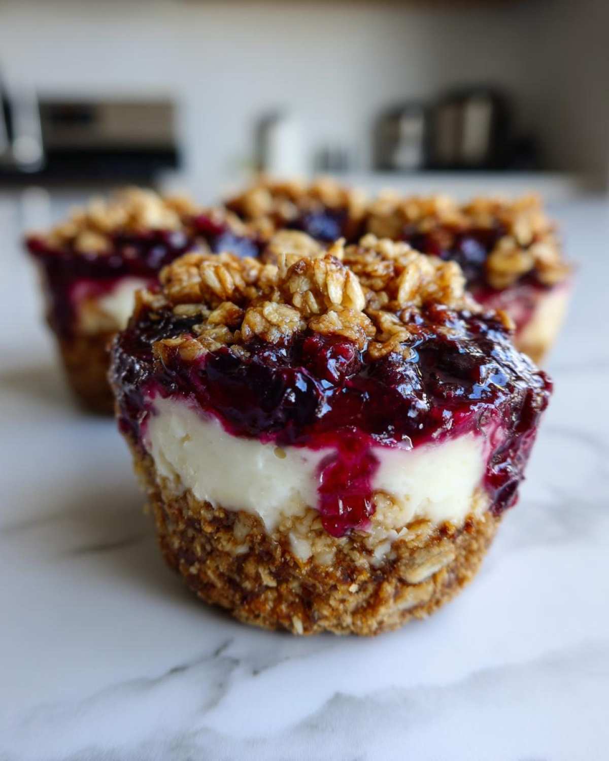 A close-up of a No-Bake Blueberry Cheesecake Oat Cup showing the crust, creamy filling, blueberry topping, and oat crumble.