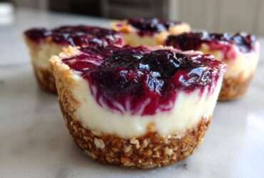 A close-up of a No-Bake Blueberry Cheesecake Oat Cup showing the thick oat crust, creamy filling, and glossy blueberry topping.