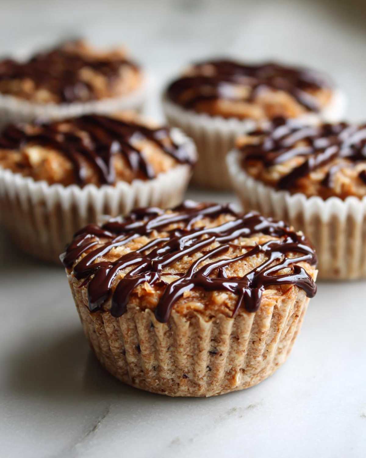 A close-up of a No-Bake Chocolate Coconut Protein Cup drizzled with dark chocolate.