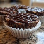 Close-up of a No-Bake Chocolate Coconut Protein Cups drizzled with melted chocolate, sitting in a white paper liner.