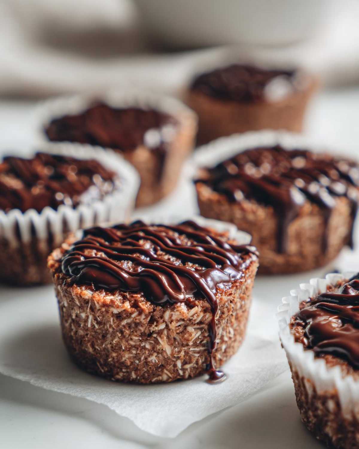 A close-up of a No-Bake Chocolate Coconut Protein Cup topped with drizzled chocolate ganache.
