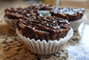 Close-up of a No-Bake Chocolate Coconut Protein Cups drizzled with melted chocolate, sitting in a white paper liner.