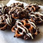 Close-up of several No-Bake Chocolate Covered Pretzel Clusters drizzled with white chocolate.