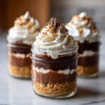 Close-up of a layered No-Bake Chocolate Peanut Butter Pie Jars topped with whipped cream and chocolate shavings.