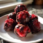 A stack of No-Bake Chocolate Strawberry Yogurt Clusters partially dipped in dark chocolate on a white plate.