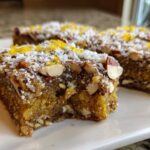 Close-up of three No-Bake Lemon Almond Date Bars topped with shredded coconut, sliced almonds, and bright yellow lemon zest.