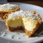 A close-up of a No-Bake Lemon Coconut Cheesecake Cup with a bite taken out, topped with shredded coconut.