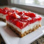 A close-up of a square slice of No-Bake Strawberry Pretzel Dessert Bars showing the pretzel crust, cream cheese layer, and strawberry gelatin topping.