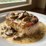 A thick, seared pork chop smothered in creamy Dijon sauce and sliced mushrooms, part of the One-Pan Creamy Dijon Pork Chops with Mushrooms recipe.