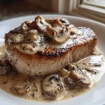 A thick, seared pork chop smothered in creamy Dijon sauce and sliced mushrooms, part of the One-Pan Creamy Dijon Pork Chops recipe.