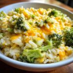 Close-up of a white bowl filled with One-Pot Creamy Broccoli Cheddar Rice, featuring melted cheese and bright green broccoli florets.