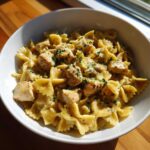 A close-up of One-Pot Creamy Lemon Pepper Chicken Pasta featuring bowtie pasta and cubed chicken in a rich sauce.
