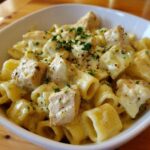 A close-up of One-Pot Creamy Lemon Pepper Chicken Pasta served in a white bowl, topped with parsley.