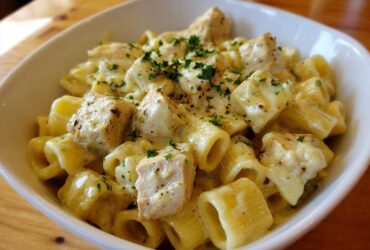 A close-up of One-Pot Creamy Lemon Pepper Chicken Pasta served in a white bowl, topped with parsley.