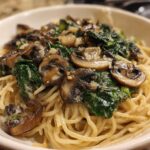 Close-up of One-Pot Creamy Mushroom Spinach Ramen noodles topped with sautéed mushrooms and wilted spinach.
