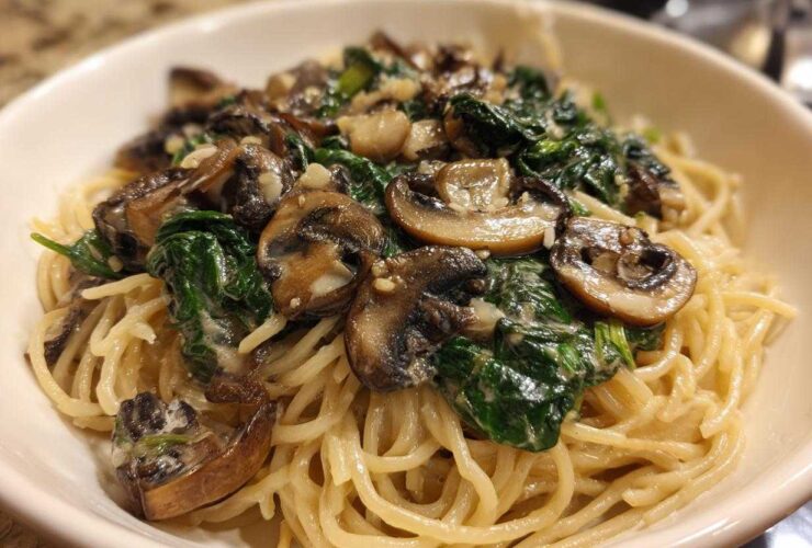 Close-up of One-Pot Creamy Mushroom Spinach Ramen noodles topped with sautéed mushrooms and wilted spinach.