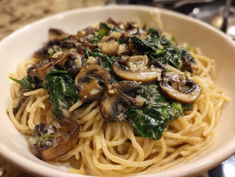 Close-up of One-Pot Creamy Mushroom Spinach Ramen noodles topped with sautéed mushrooms and wilted spinach.