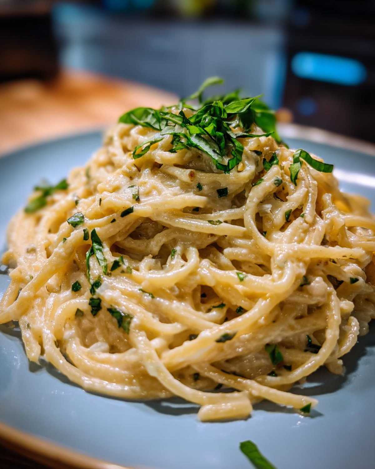 Close-up of a serving of One-Pot Creamy White Bean Lemon Pasta, topped with fresh basil.