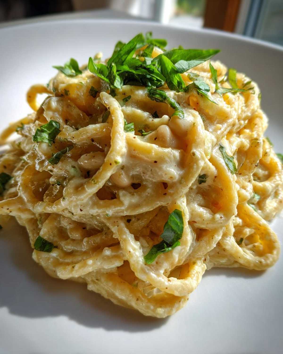 Close-up of One-Pot Creamy White Bean Lemon Pasta tossed in a rich sauce and topped with fresh green herbs.